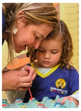 Professora ajudando uma criança em atividade com tinta
