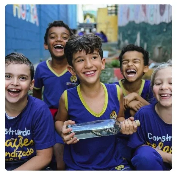 Crianças da Plaft sorrindo juntas no pátio da escola durante uma atividade